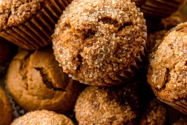 close-up photo of many pumpkin muffins topped with coarse sugar.
