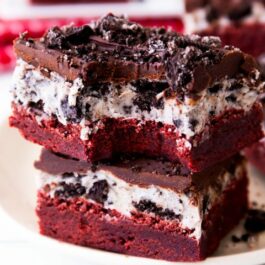 stack of red velvet Oreo brownies on a white plate with a bite taken from one