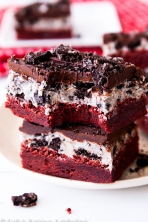 stack of red velvet Oreo brownies on a white plate with a bite taken from one