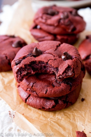 stack of red velvet chocolate chip cookies with a bite taken from the top cookie