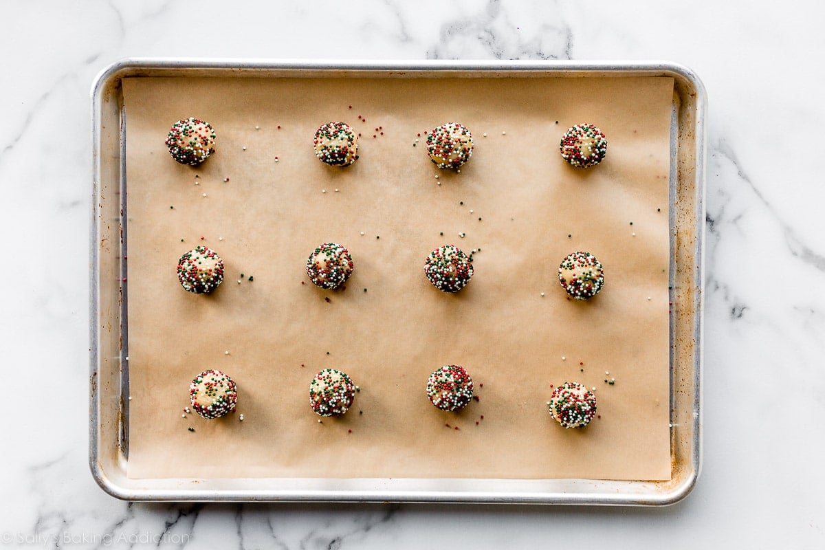 cookie dough balls arranged on baking sheet lined with parchment paper.