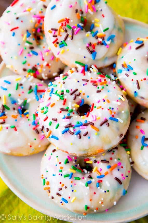 baked funfetti donuts topped with vanilla glaze and sprinkles on a white plate