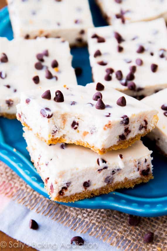 chocolate chip cheesecake bars on a blue plate with a bite taken from one