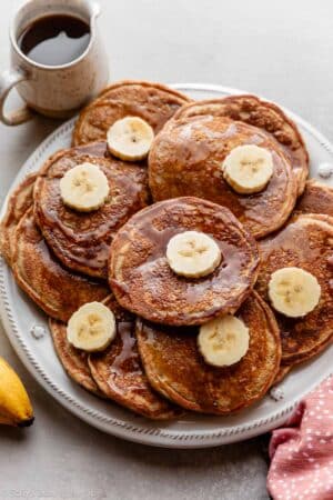 bite plate of whole wheat banana pancakes with maple syrup and banana slices.
