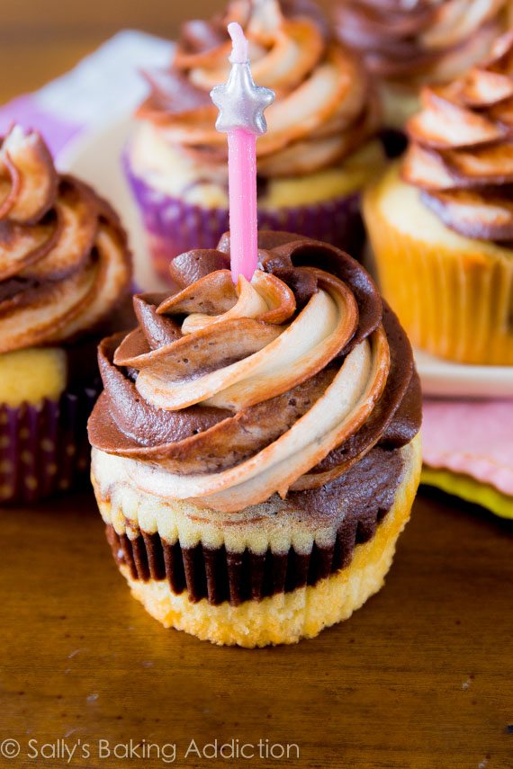 marble cupcakes topped with chocolate vanilla swirl frosting with a pink candle
