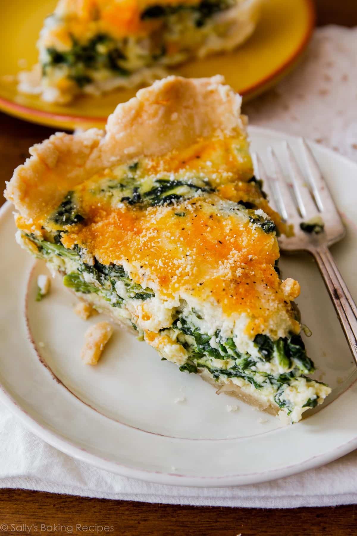 slice of spinach quiche on white plate.