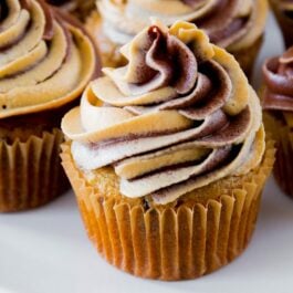 banana chocolate chip cupcakes topped with chocolate peanut butter swirl frosting on a white plate