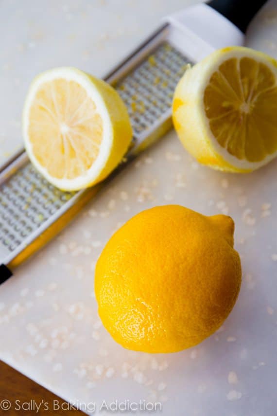 lemons on a white cutting board with a zester