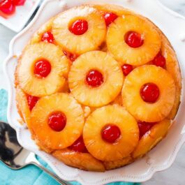 overhead image of pineapple upside down cake on a white serving plate
