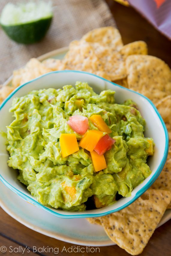 mango guacamole in a white bowl with chips on a plate