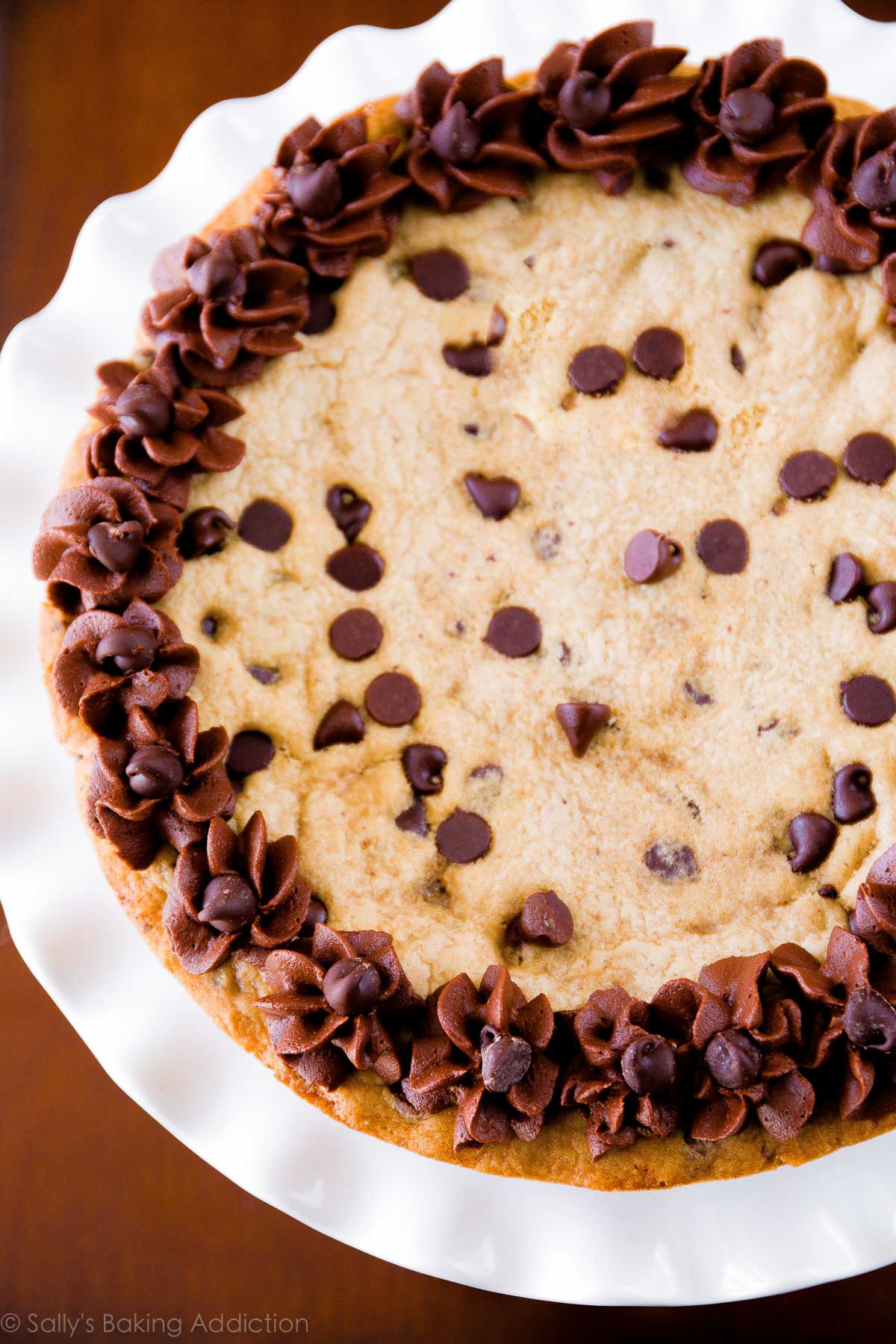 chocolate chip cookie cake with chocolate buttercream on a white cake stand