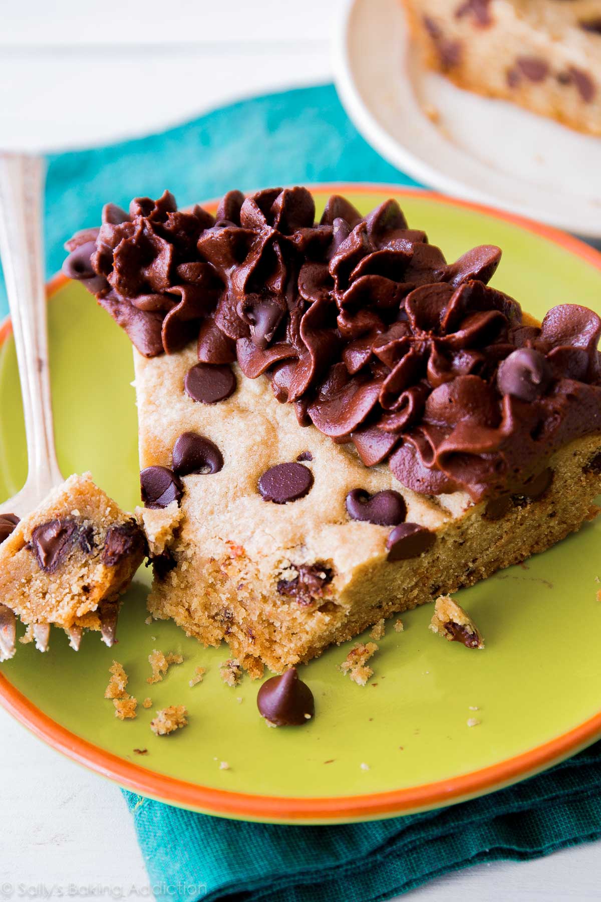 slice of chocolate chip cookie cake on a green plate with a fork