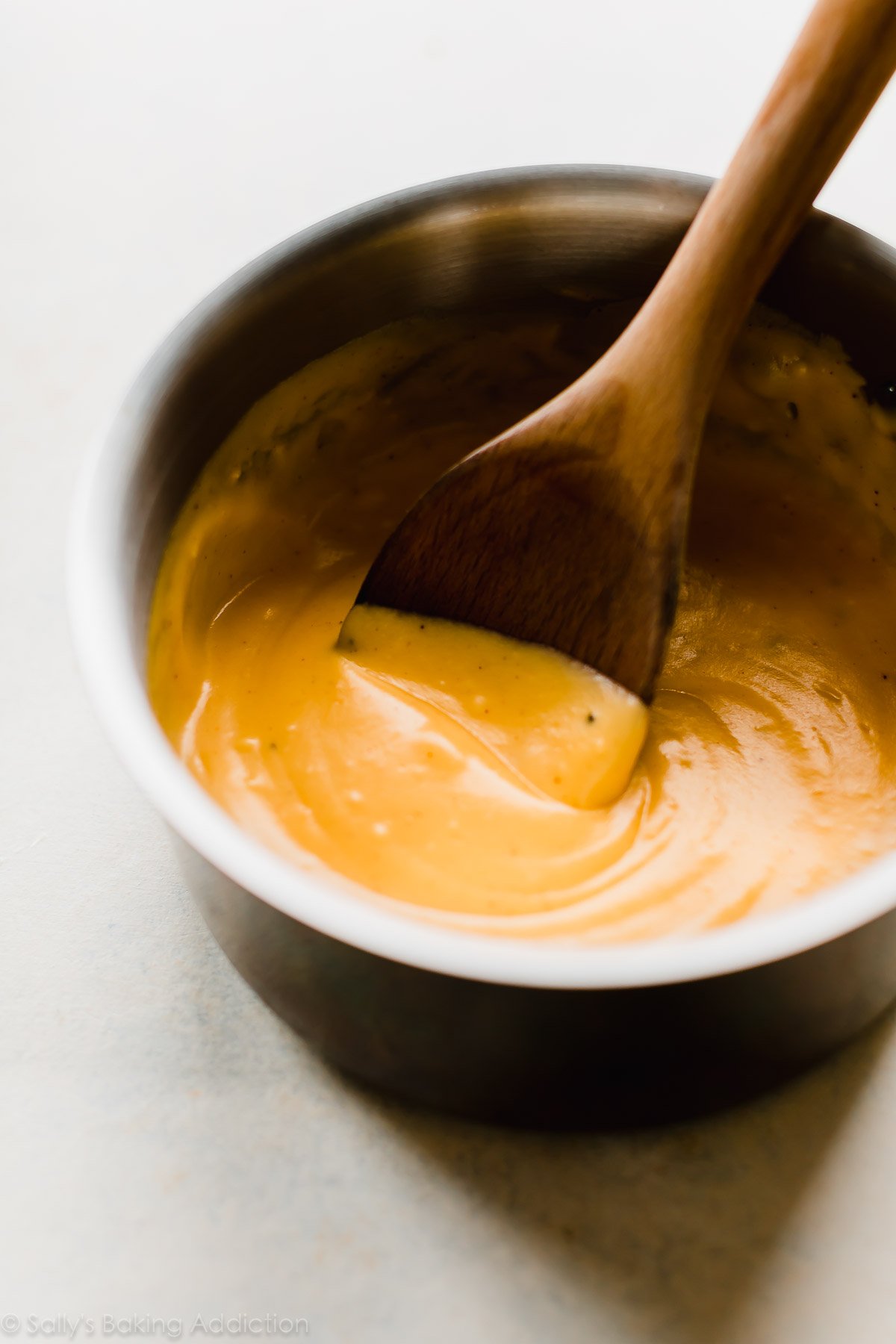 nacho cheese sauce in a saucepan with a wooden spoon