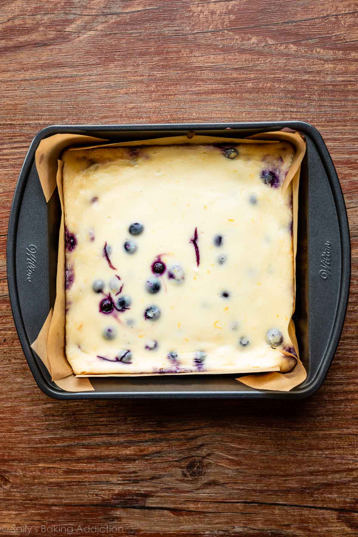 square baking pan of baked and cooled blueberry cheesecake bars.