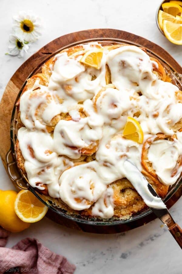 pan of lemon sweet rolls with cream cheese icing and lemon slices on top.