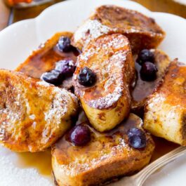 mini french toast bites with maple syrup and blueberries on a white plate with a fork