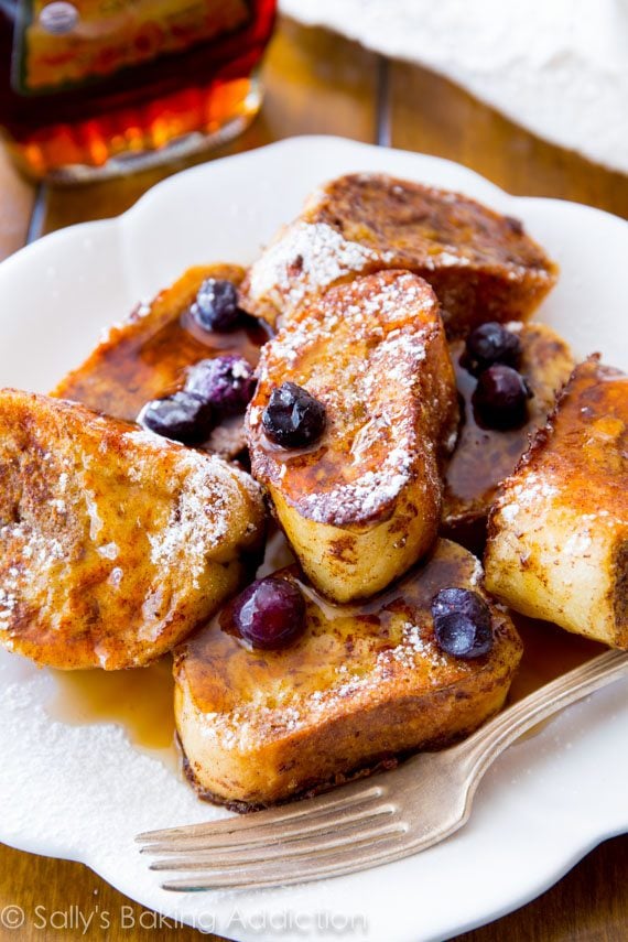 mini french toast bites with maple syrup and blueberries on a white plate with a fork