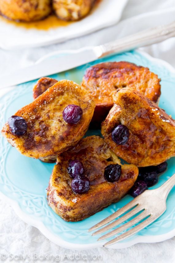 mini french toast bites with maple syrup and blueberries on a blue plate with a fork