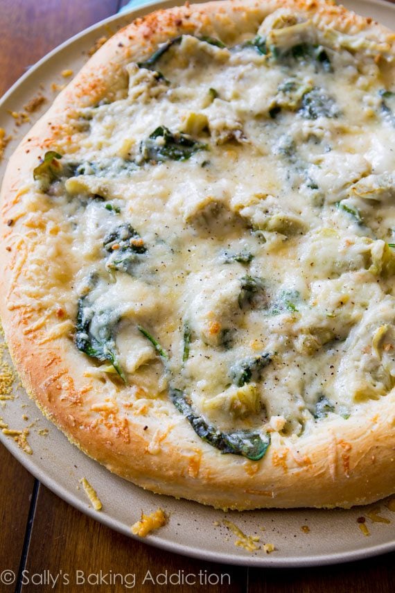 spinach artichoke pizza on a pizza pan