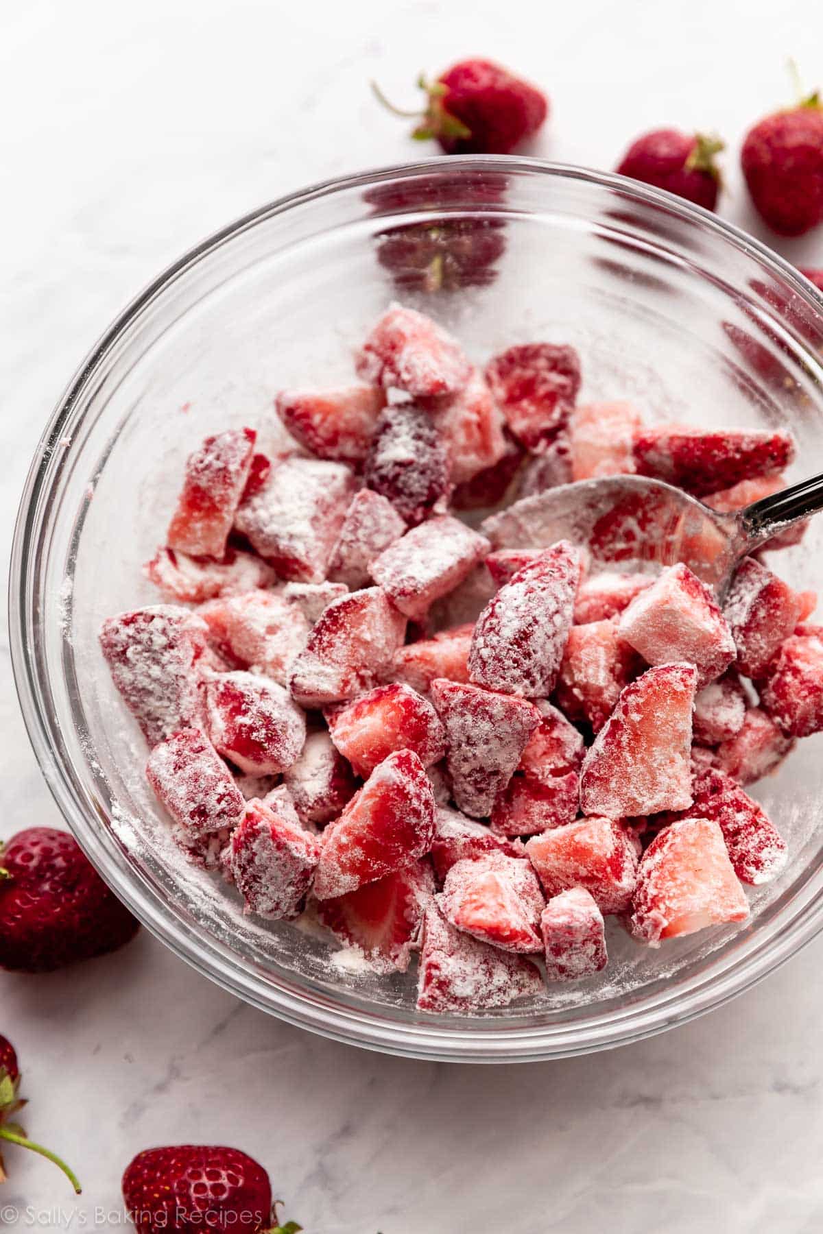 flour-dusted strawberries in glass bowl.