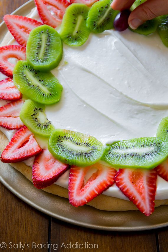 adding fruit toppings to fruit pizza