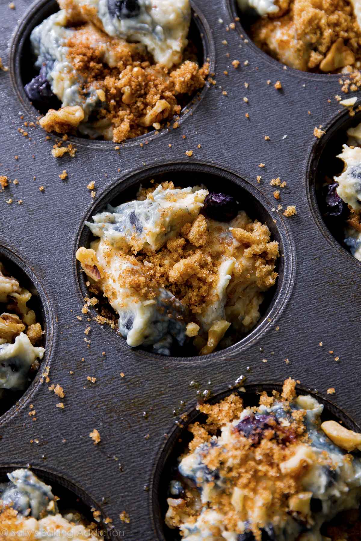 Blueberry muffin batter in muffin pan with streusel topping