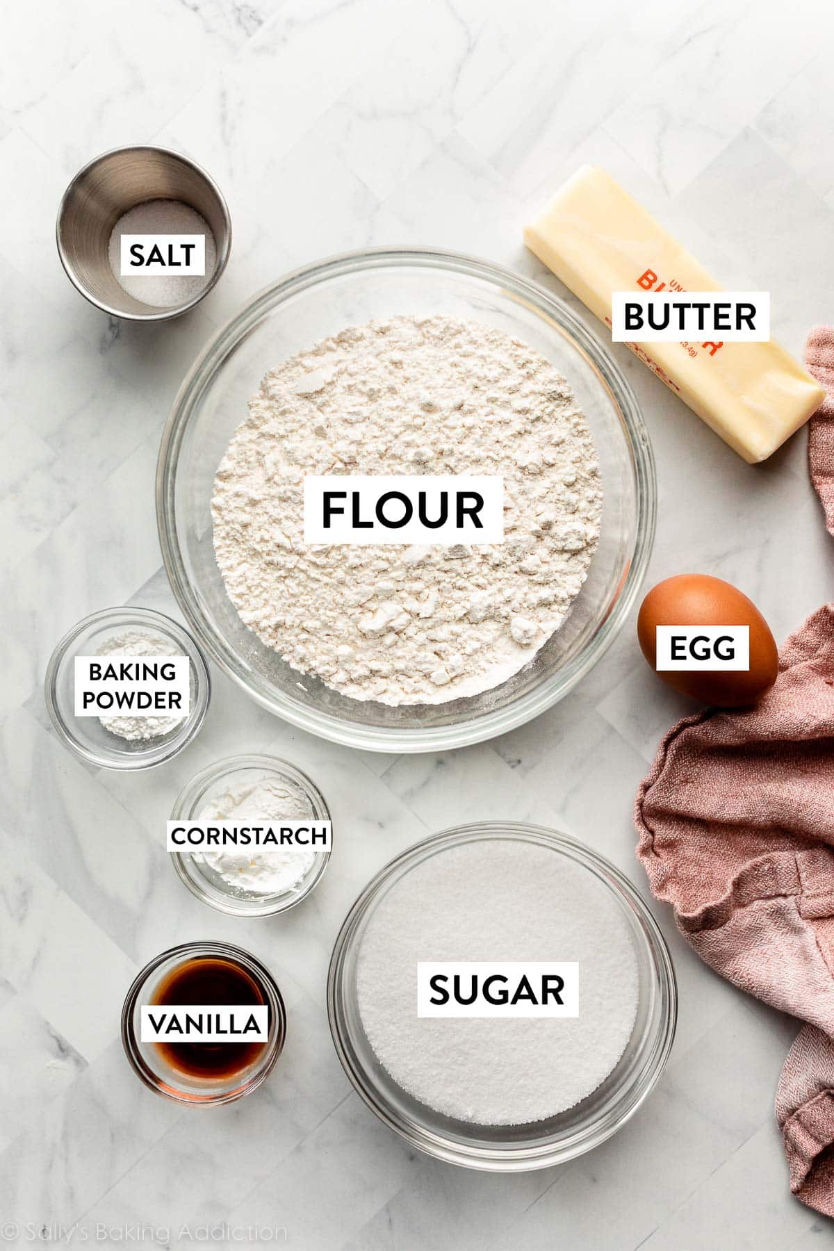 ingredients displayed in bowls including flour, sugar, baking powder, cornstarch, vanilla, salt, plus butter and 1 egg.