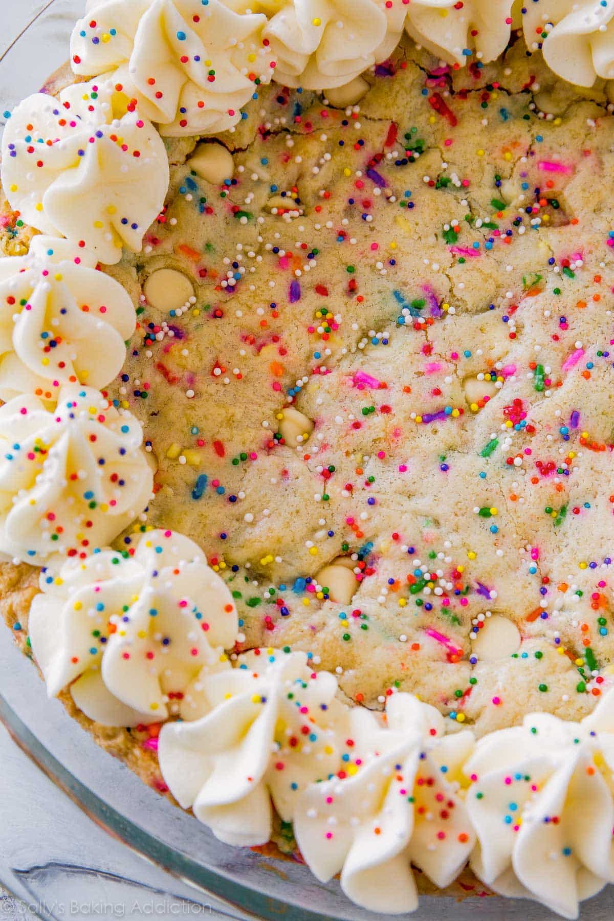 funfetti sugar cookie cake with piped frosting decorations and sprinkles in a glass baking dish