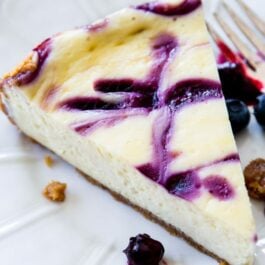 slice of blueberry swirl cheesecake on a white plate with a fork