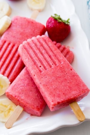 strawberry banana popsicles on a white serving tray