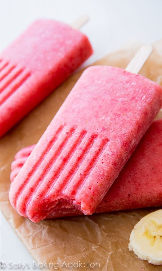 strawberry banana popsicles with a bite taken from one