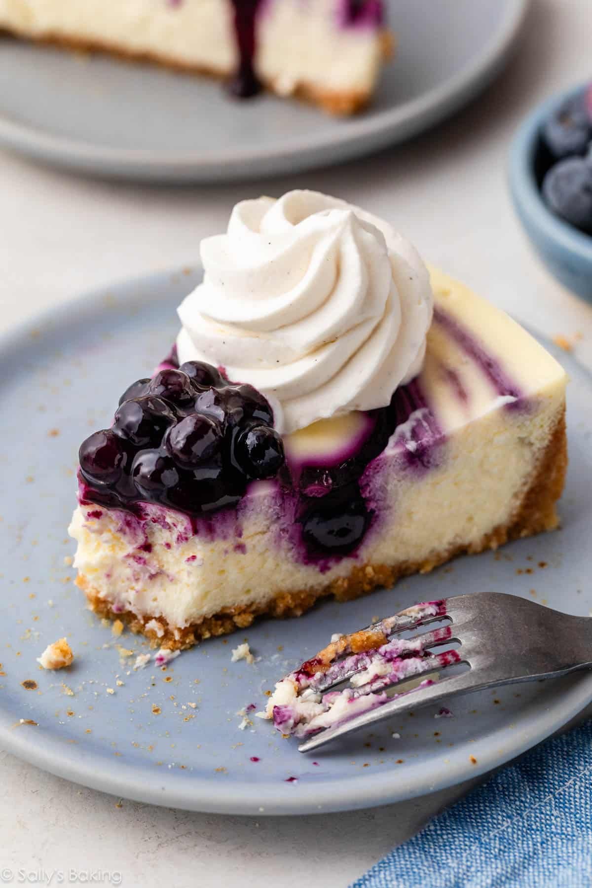 slice of blueberry swirl cheesecake on blue plate.