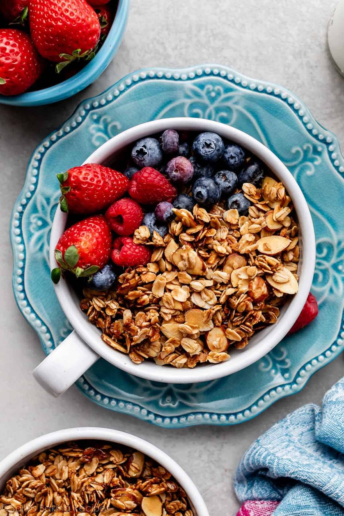 bowl of homemade granola with fresh berries on blue plate.