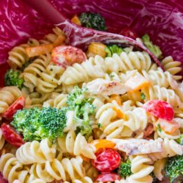 creamy chicken pasta salad in a pink mixing bowl with a spatula