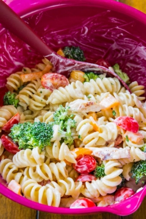 creamy chicken pasta salad in a pink mixing bowl with a spatula