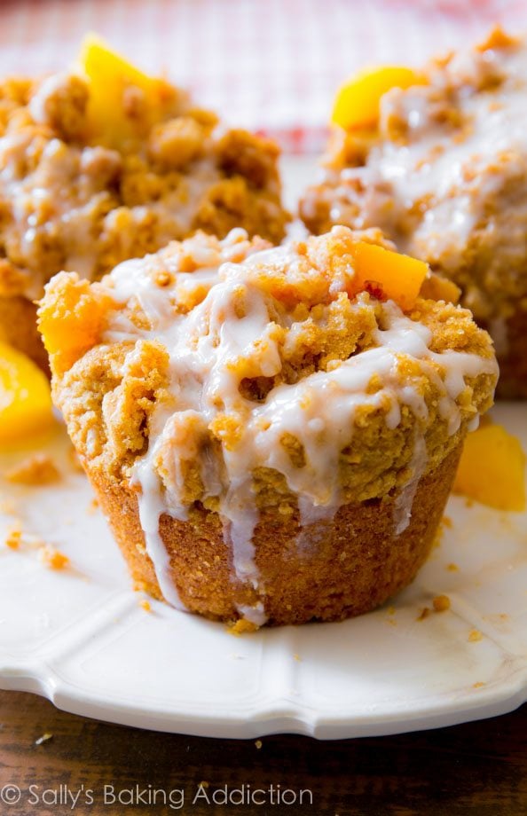peach streusel muffins with vanilla glaze on a white plate