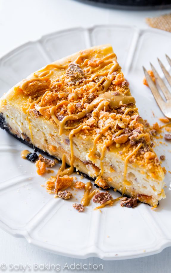 slice of peanut butter Butterfinger cheesecake on a white plate with a fork