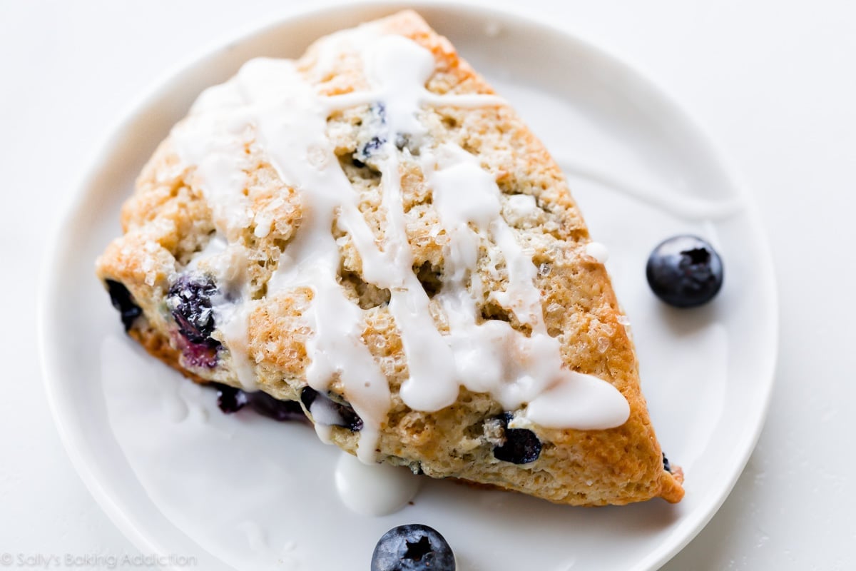 Blueberry scone with vanilla icing on a white plate