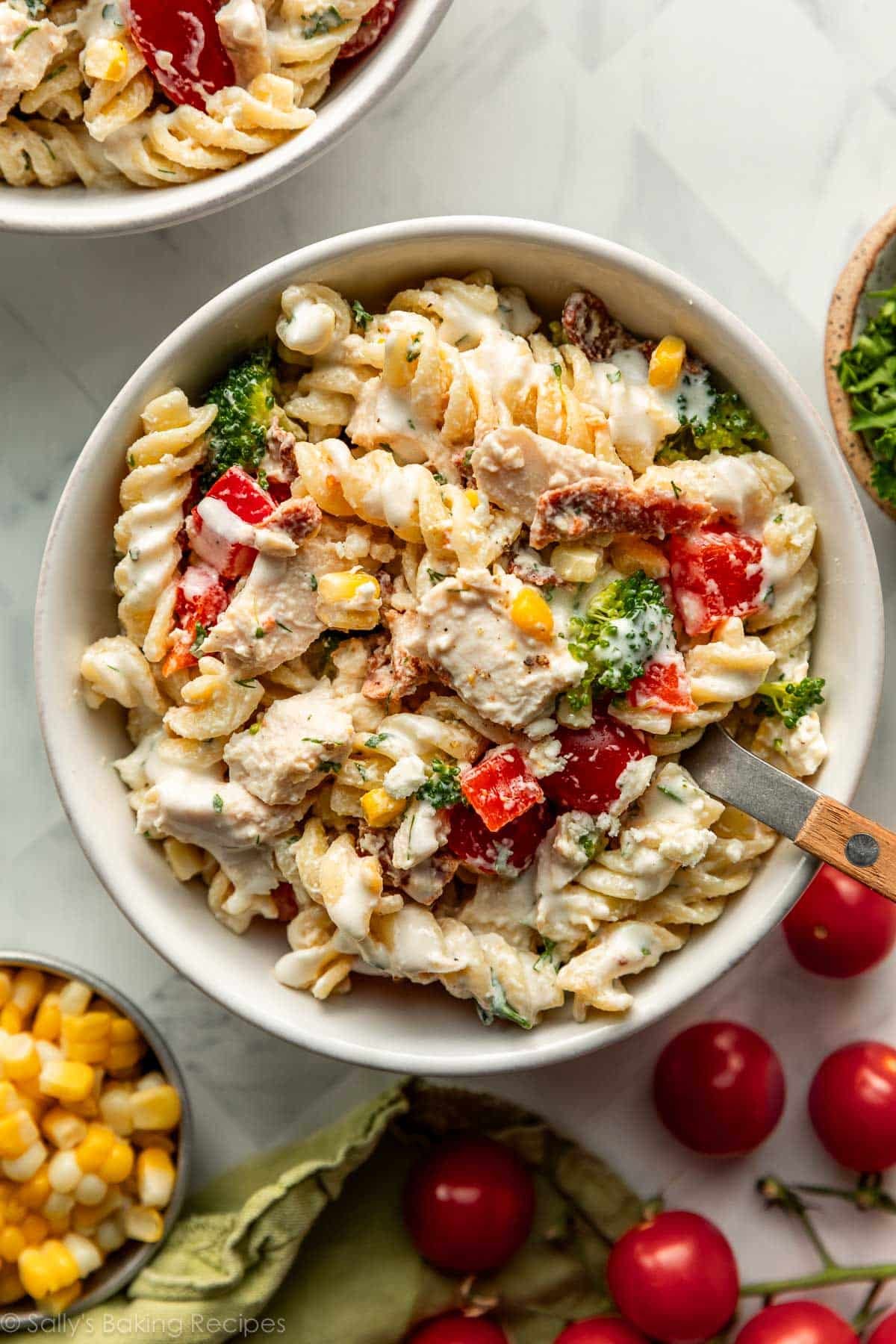 serving bowl of creamy chicken pasta salad with broccoli and red bell peppers.