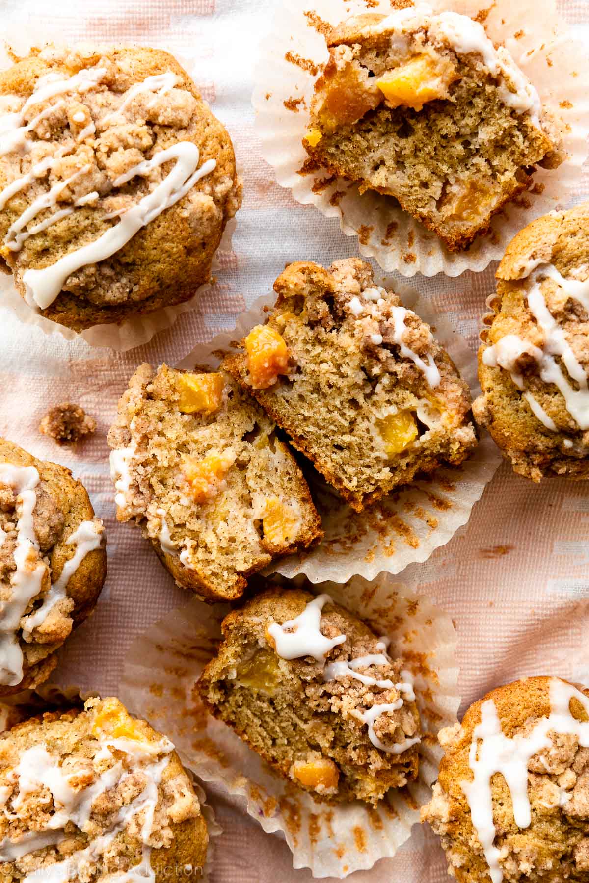 peach muffins cut open with crumb topping and vanilla icing.