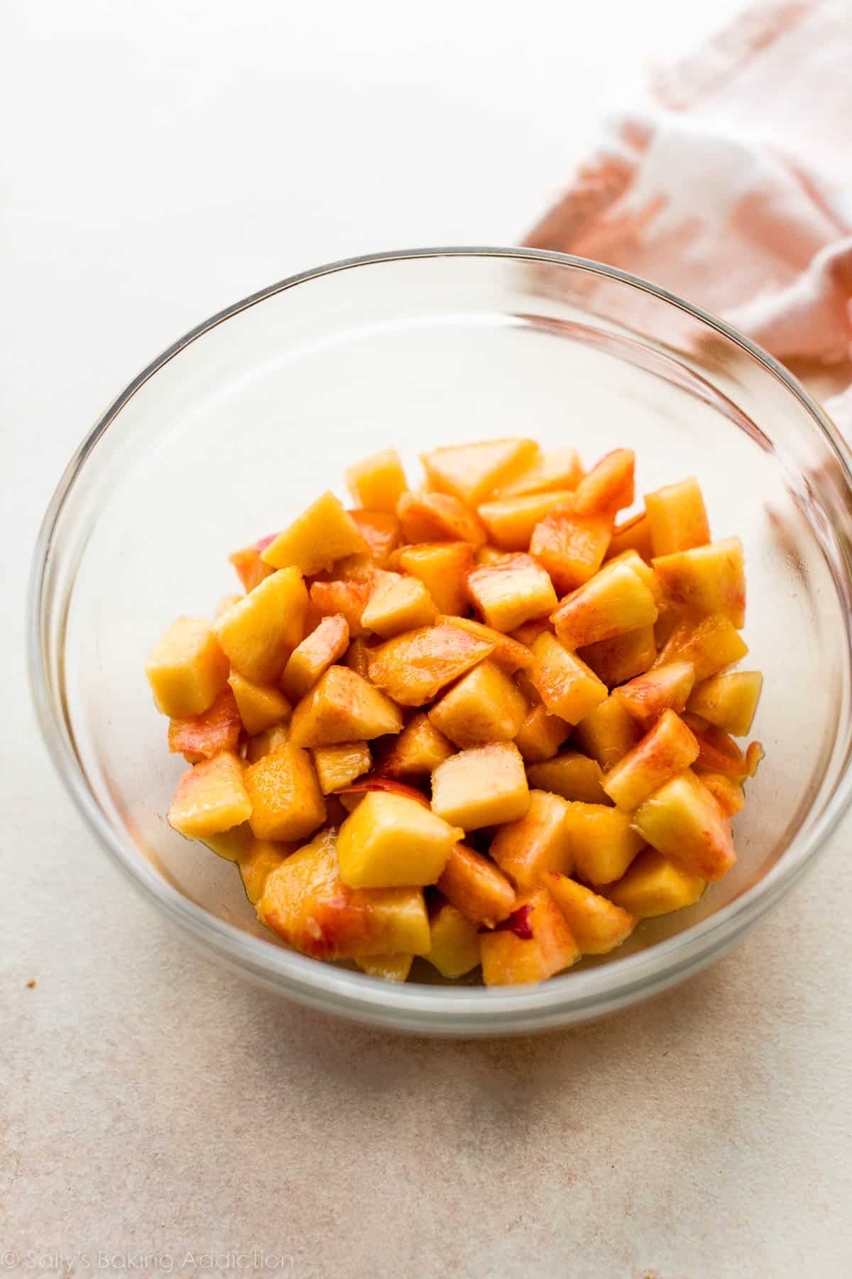 peeled and chopped peaches in glass bowl.