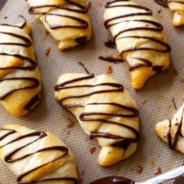 chocolate crescents with chocolate drizzle on a silpat baking mat