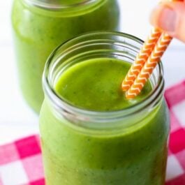 green smoothie in glasses with straws