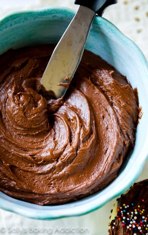 milk chocolate frosting in a blue bowl with a spatula