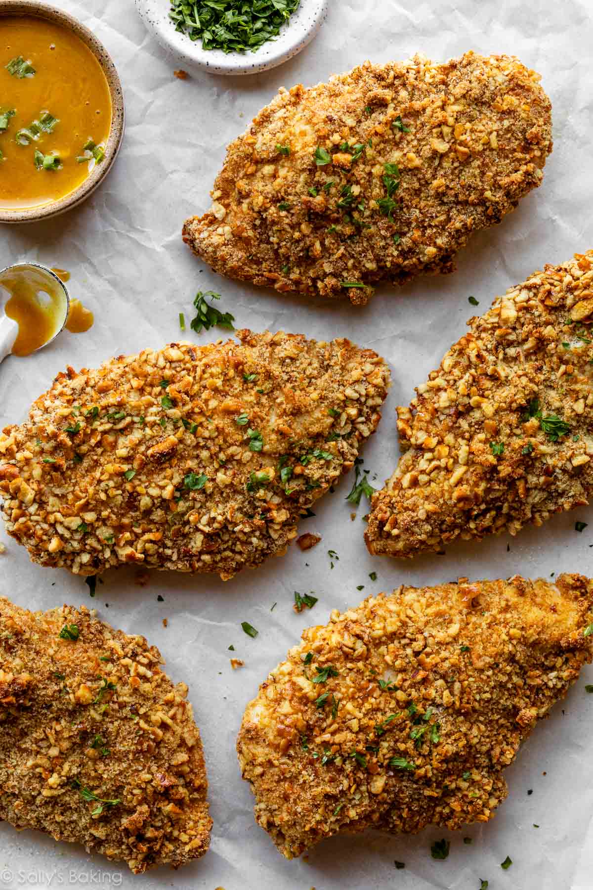 pretzel-crusted chicken on parchment paper with honey mustard dipping sauce.