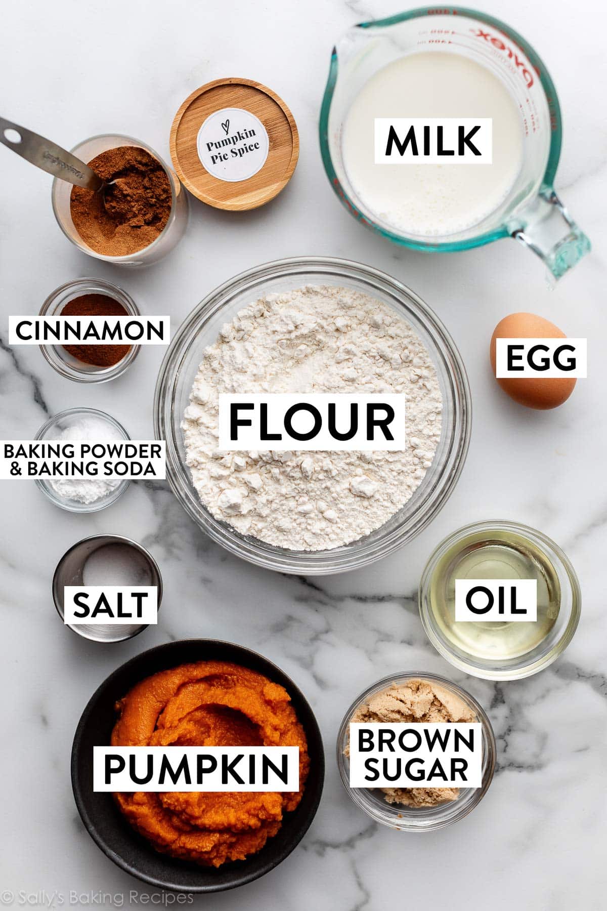 ingredients on marble counter including flour, milk, brown sugar, oil, egg, and cinnamon.