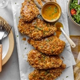 pretzel-crusted chicken on a platter with honey mustard dipping sauce.