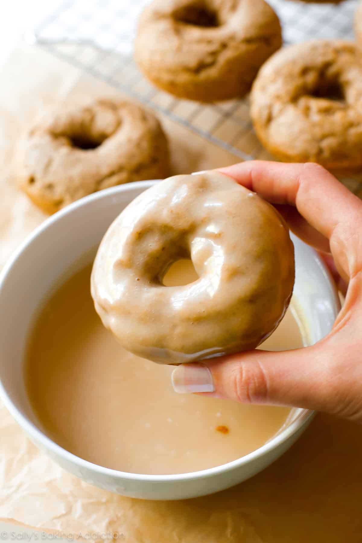 dipping baked donuts into maple icing
