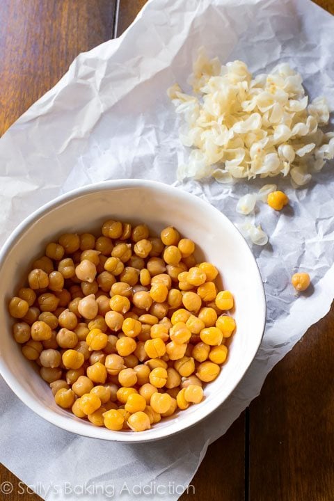 chickpeas in a white bowl with skins peeled off