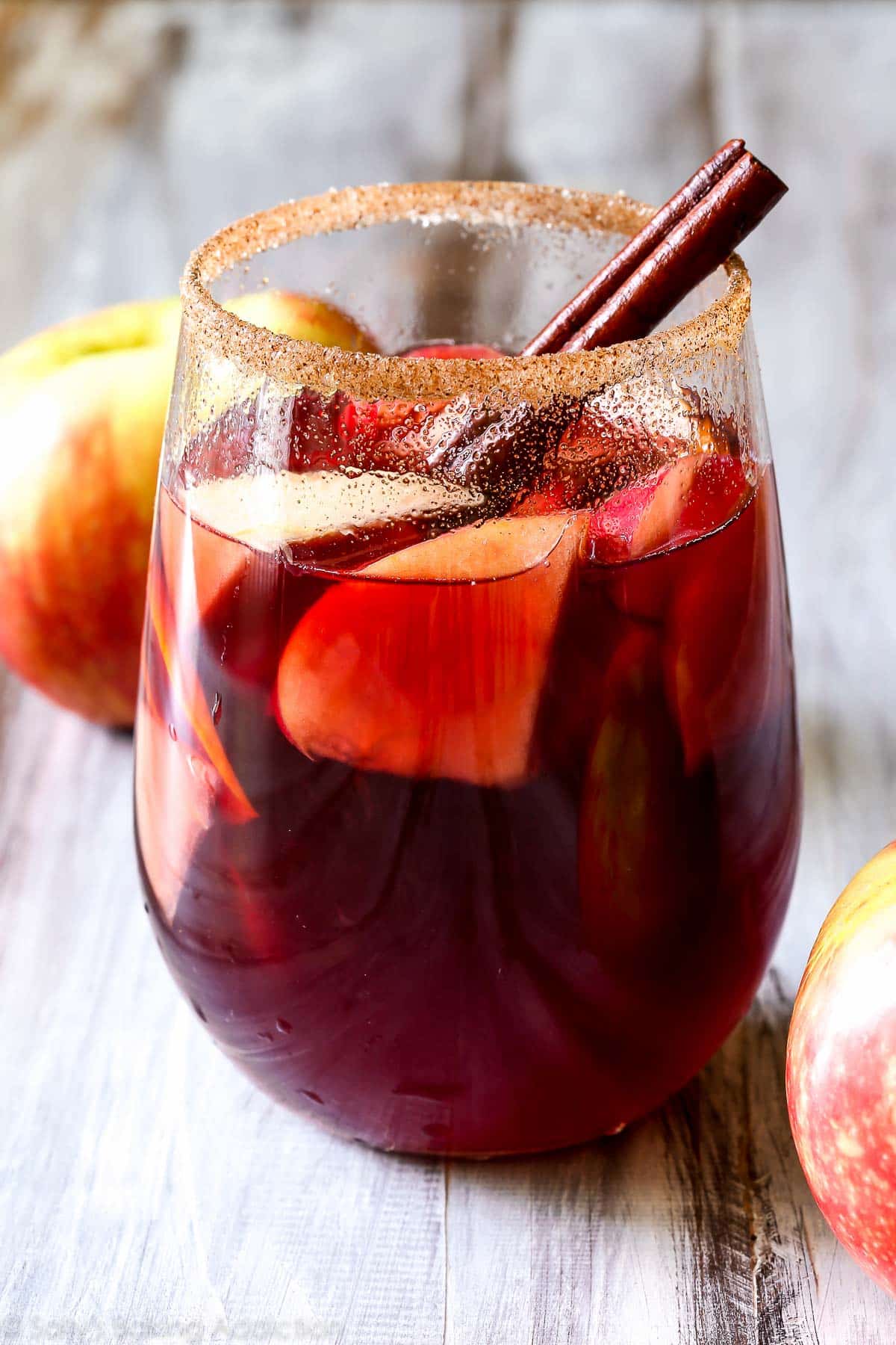 honeycrisp apple sangria with a cinnamon stick in a glass with the rim dipped in cinnamon sugar